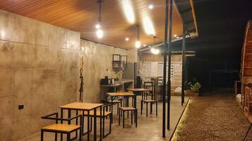Un espacio interior amplio con mesas y sillas, una pared de hormigón y un techo de madera.