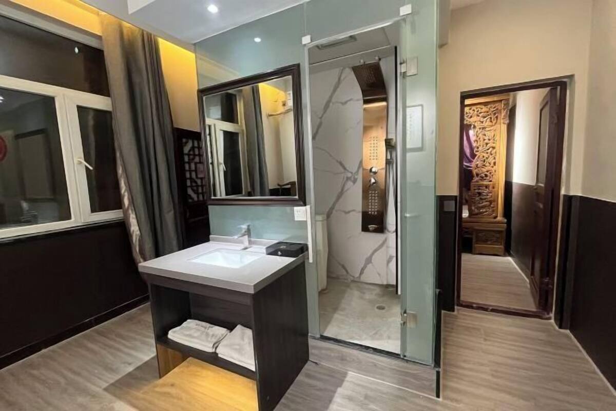 Un baño moderno con cabina de ducha de vidrio, tocador con lavamanos y espejo.