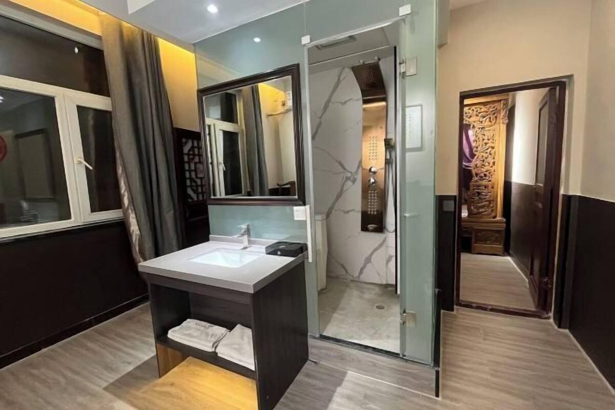Un baño moderno con cabina de ducha de vidrio, tocador con lavabo y espejo.