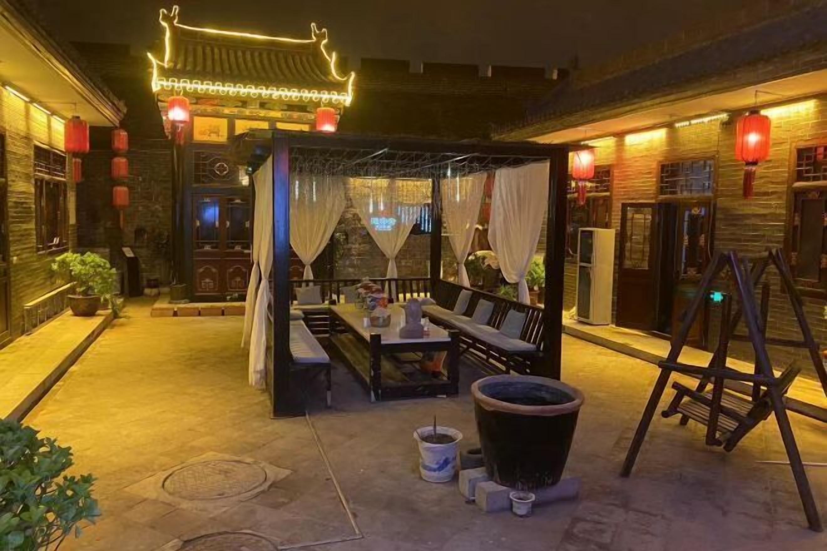 An outdoor seating area with a canopy, tables, chairs, and a traditional lantern.