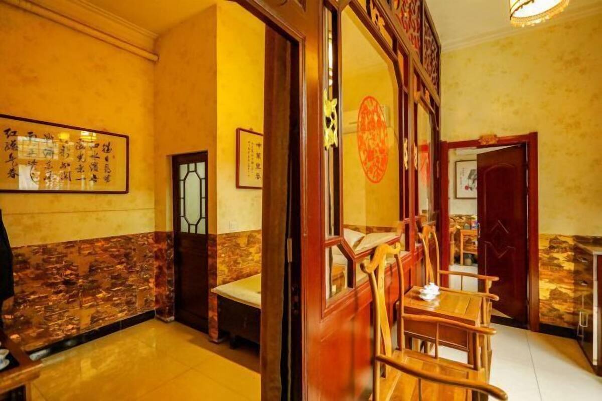 Un interior tradicional con una mesa de comedor de madera, sillas, una pared de acento de piedra y caligrafía enmarcada en la pared.