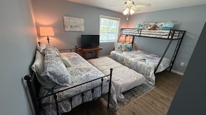 A bedroom with bunk beds, a television, and a window with blinds.
