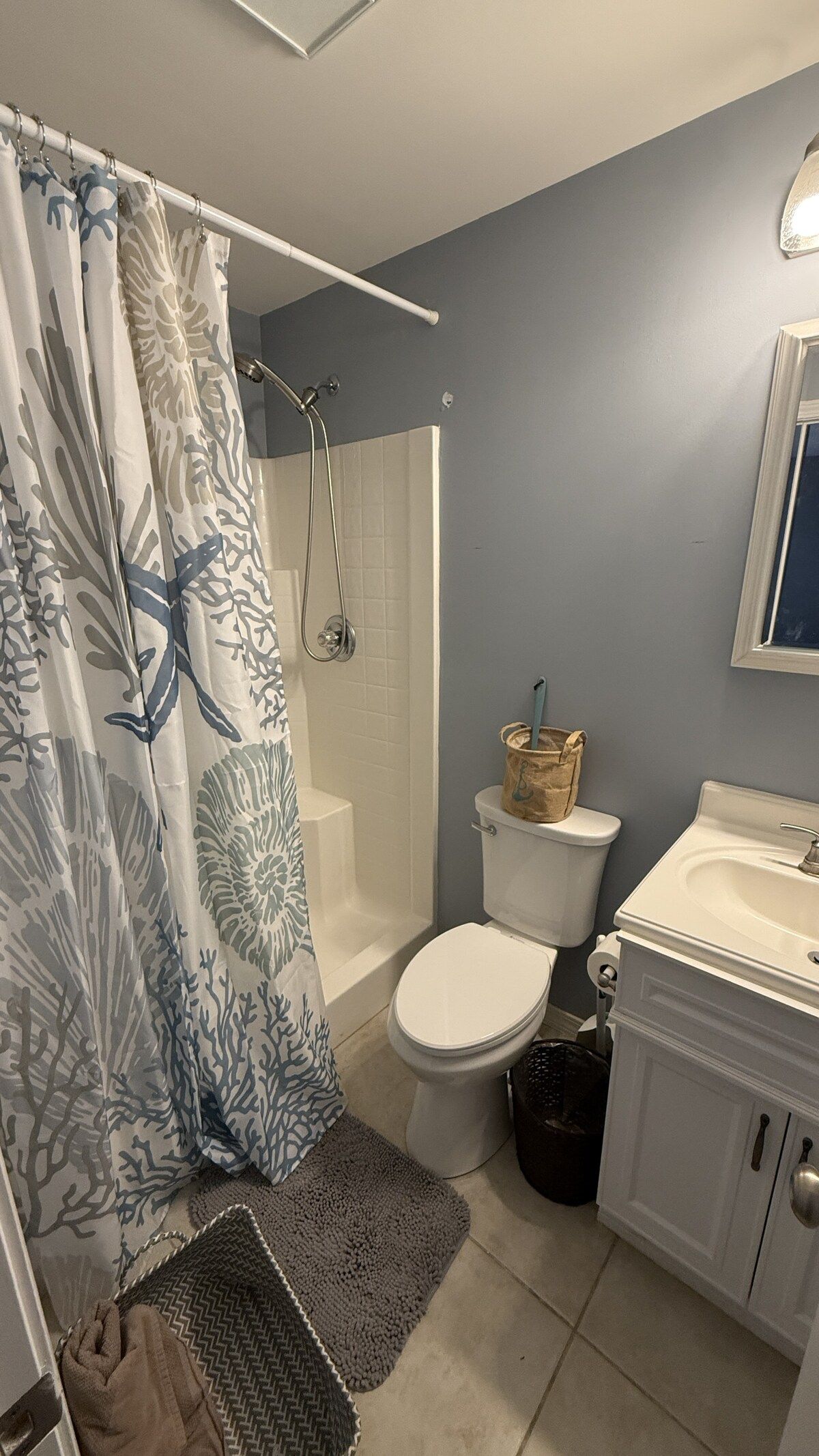 A bathroom with a shower, toilet, sink, and a towel rack.