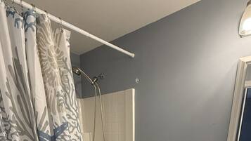 A bathroom with a shower, toilet, sink, and a towel rack.