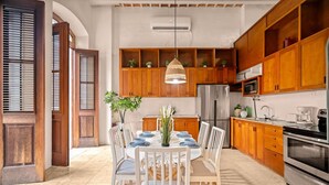 A modern kitchen with wooden cabinets, a stainless steel refrigerator, and a dining area with a table set for four.