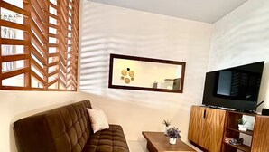 A modern living room with a brown sofa, a wooden coffee table, a TV, and a wooden cabinet. - Loft in La Veleta w/ Pool,Balcony and rooftop! Near beach cenotes downtown (Q.R.)