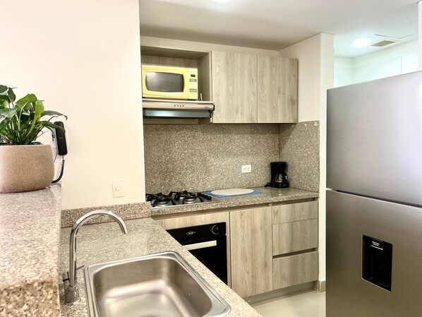 Una cocina moderna con encimeras de granito, electrodomésticos de acero inoxidable y armarios de madera.