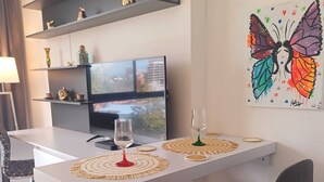 A modern living room with a white sofa, a dining table with two chairs, a TV, and a colorful butterfly painting on the wall. - Modern loft  Bogotá international center (Bogotá)