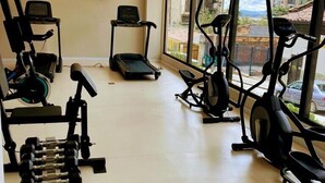 A modern gym with various exercise equipment, large windows, and a view of the city. - Modern loft  Bogotá international center (Bogotá)