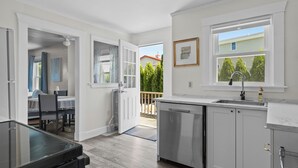 A modern kitchen with white cabinets, a stainless steel dishwasher, and a window with a view of the outside.
