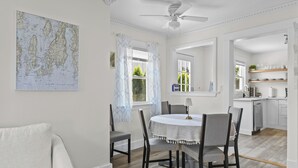 A dining area with a round table, chairs, a ceiling fan, and a map on the wall.