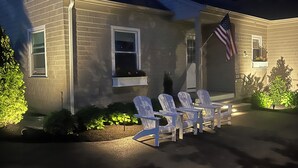 A two-story house with a porch, a flag, and outdoor seating.