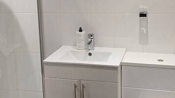Une salle de bain moderne avec une douche à parois de verre, un lavabo blanc et des toilettes.