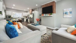 Een moderne woonkamer met een grijze bank, een salontafel en een televisie bevestigd aan een bakstenen muur.