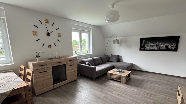 A modern living room with a wooden cabinet, a gray sofa, a coffee table, and a wall clock.