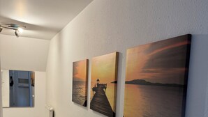 A hallway with three sunset paintings on the wall, a bench, and a radiator.