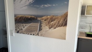 A door with a beach scene wallpaper, a wooden floor, and a kitchen area with a countertop and cabinets.
