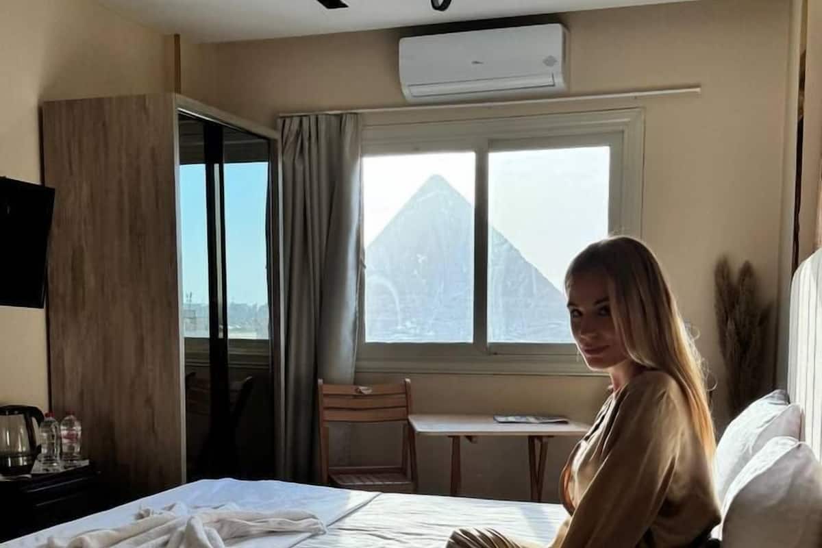 A hotel room with a bed, a desk, and a window with a mountain view.
