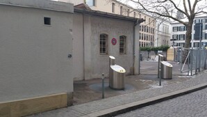Un edificio con un cartel de prohibido estacionar, un basurero y una estructura metálica en la acera.