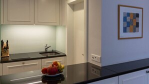 Una cocina moderna con armarios blancos, encimera negra y un frutero.