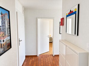 Un pasillo con una puerta blanca, un cuadro en la pared y un armario.