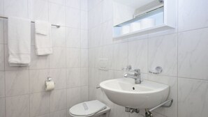 A bathroom with a white sink, toilet, and towel rack. - Practical studio at trendy location - Stork 22 (Zürich)