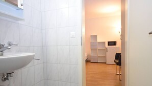 A modern bathroom with a white sink and tiled walls. - Practical studio at trendy location - Stork 22 (Zürich)