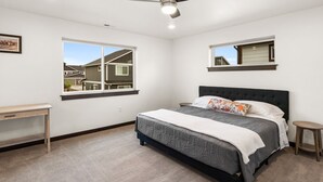 A bedroom with a bed, a desk, a ceiling fan, and two windows. - Fireside Retreat (Belgrade)