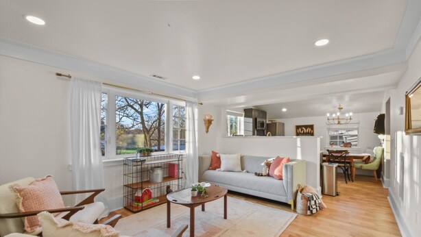 A spacious living room with a sofa, chairs, and a coffee table. There is a dining area with a table and chairs, and a kitchen in the background. - Raspberry Retreat Cottage (Lovettsville)