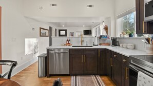 A modern kitchen with dark wood cabinets, stainless steel appliances, and a large island. - Raspberry Retreat Cottage (Lovettsville)