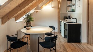 Una cocina moderna con vigas de madera, una isla central y una zona de comedor con sillas.