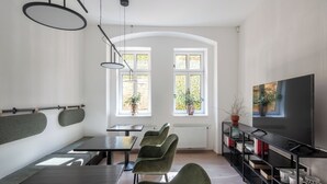 Una sala de estar moderna con comedor, ventanas amplias y un televisor de pantalla plana.