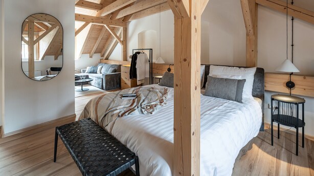 Un dormitorio amplio con una cama grande, un banco y un escritorio con una silla.