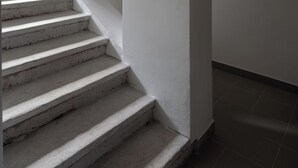 Una escalera conduce a una zona de cocina con paredes blancas y un letrero que indica la cocina.
