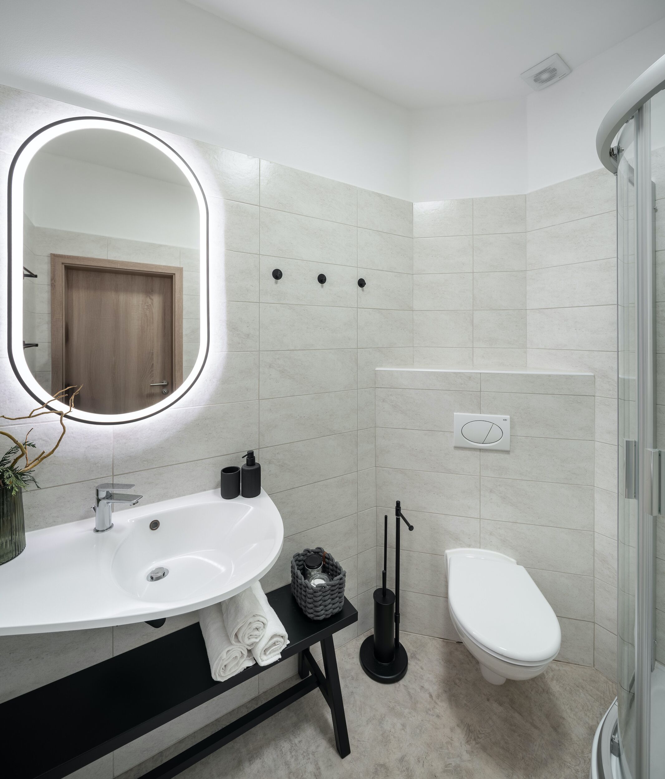 A modern bathroom with a white sink, mirror, and toilet.
