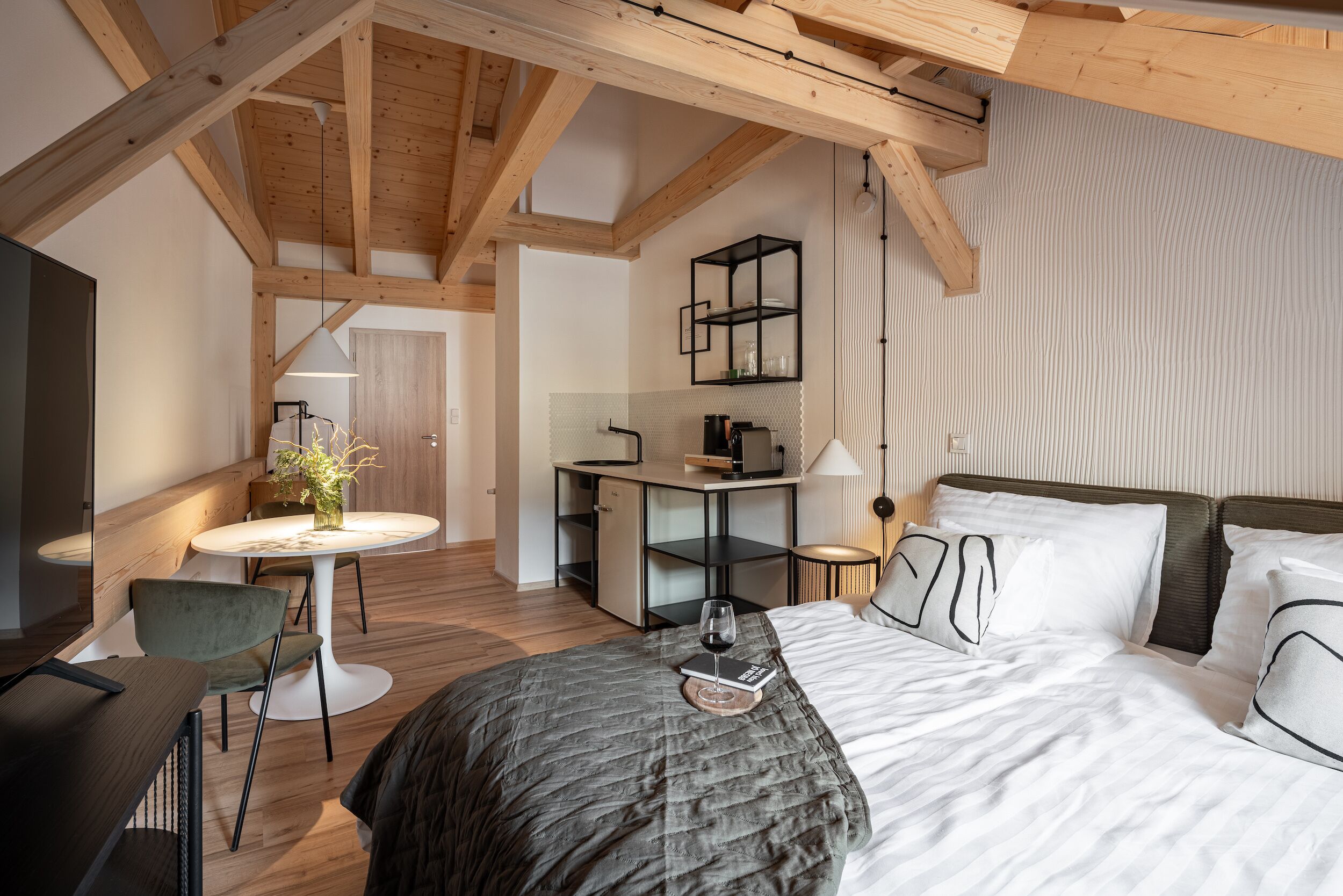 A modern bedroom with a large bed, a desk, and a chair.