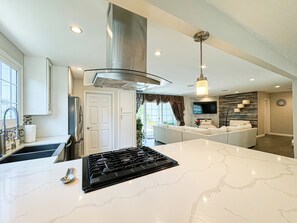 Enjoy cooking in this well-equipped kitchen with a large island, stove, and range hood.