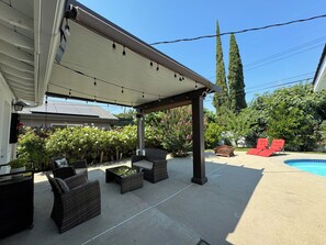 Relax in style on the covered patio, surrounded by lush greenery and a sparkling pool.