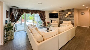 Relax in this inviting living space with a large sofa, flat-screen TV, and natural views.