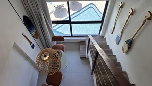 A modern interior with a staircase, a view of the outside, and various decorative items. - Duplex Vista Piscina 313c Bela Vista bLP (Ipojuca)