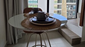 A dining area with a round table, two chairs, a woven placemat, and a black teapot on a tray. - Duplex Vista Piscina 313c Bela Vista bLP (Ipojuca)