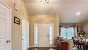 A hallway with wooden flooring, a rug, a dining area with chairs and a table, and a door with frosted glass panels. - Welcome to Your Home Away From Home (Florence)