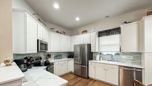 A modern kitchen with white cabinets, stainless steel appliances, and a marble countertop. - Welcome to Your Home Away From Home (Florence)