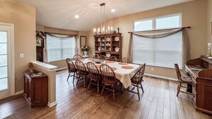 A dining room with a wooden table, chairs, a chandelier, and a china cabinet. - Welcome to Your Home Away From Home (Florence)