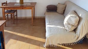 Un salon avec une table à manger en bois, un canapé et un tableau accroché au mur.