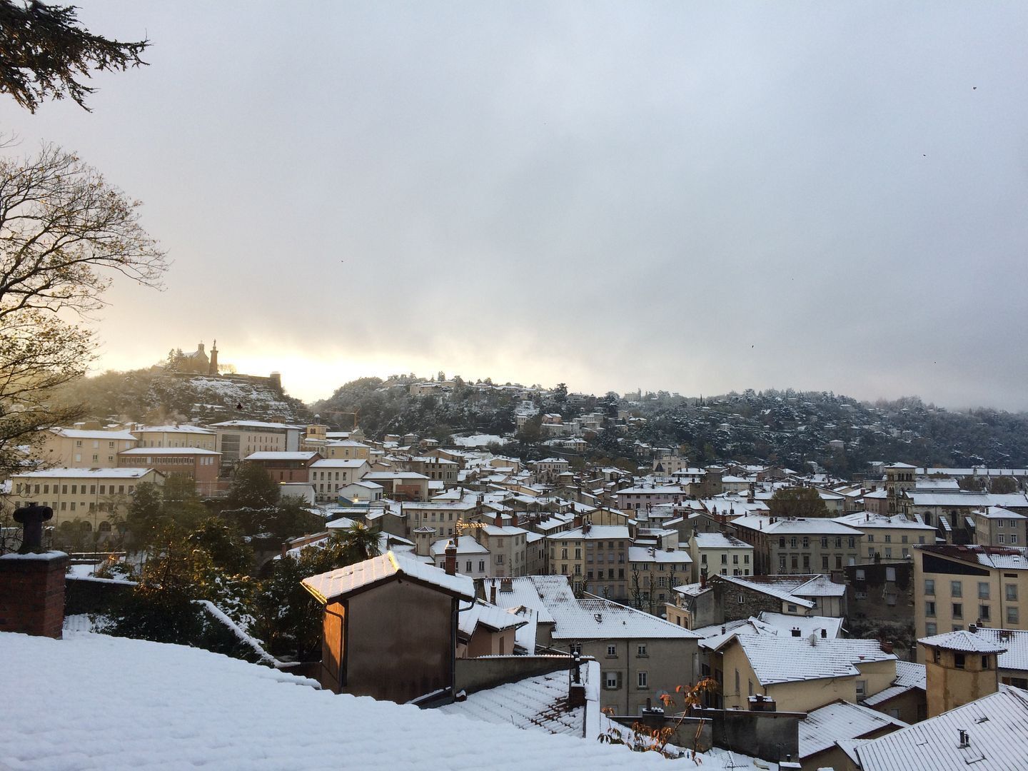 Une ville enneigée, avec des bâtiments historiques et une église imposante qui se dresse sur une colline.