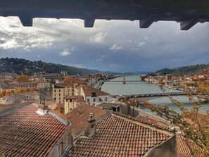 A panoramic view of a historic city with terracotta-roofed buildings, a river, and a bridge. - La Bâtie (Vienne)