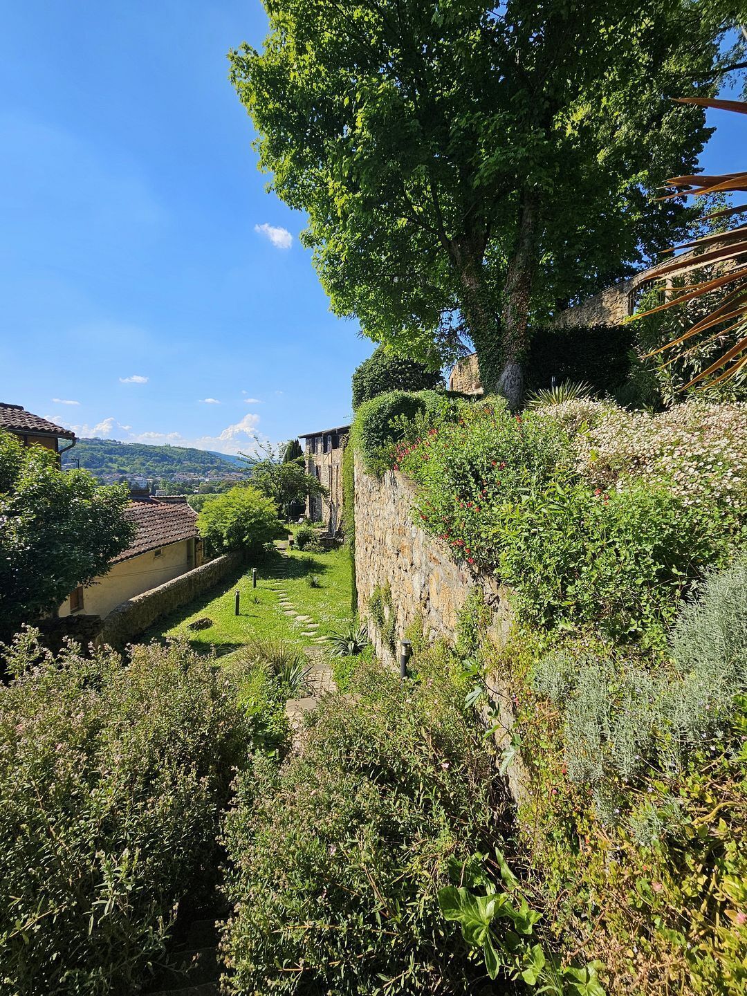 Mural de pedra com jardim e vista para um vale.