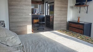 Ein Schlafzimmer mit einem Bett, einem Schreibtisch und einem an der Wand befestigten Fernseher.