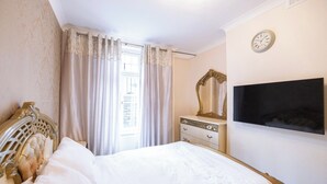 Ein Schlafzimmer mit Bett, Schminktisch, Spiegel und Fernseher.
